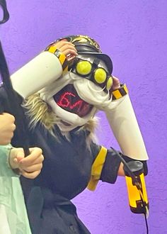 a person in costume holding a hair dryer and blow dryer to their face