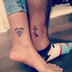 two people with matching tattoos on their feet, one has a key and the other has a heart