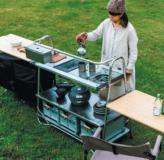 a woman standing next to a table with pots and pans on top of it