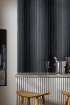 two wooden stools in front of a wall with vertical blinds on the side and behind them