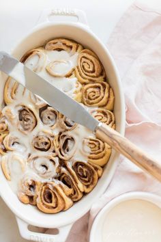 a pan filled with cinnamon rolls and icing