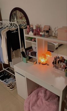 a white desk topped with lots of bottles and candles next to a mirror on top of a wall