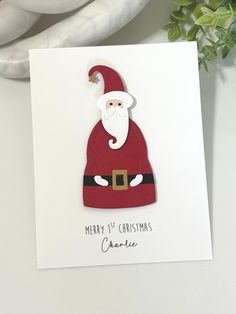 a christmas card with a santa clause on it next to a potted green plant