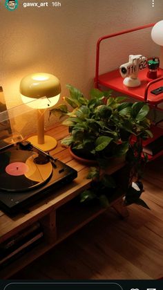 a record player sitting on top of a wooden table next to a potted plant