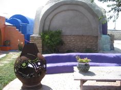 two vases sitting on top of a table in front of a stone wall and purple cloth