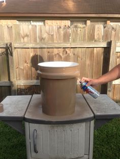 a man is painting the outside of an outdoor stove with a spray bottle in his hand