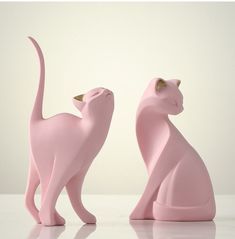 two pink cat figurines sitting next to each other