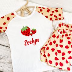 These Children's pyjamas come in a super soft white cotton, with a peach colour strawberry print on the top back, sleeve and shorts. The pyjamas have an original hand designed 3 strawberries on the front in a flocking for extra softness, finished off in a matching red personalised name. The Pyjamas are short sleeve with knee length shorts for cooler summer nights, with a elastic drawstring waist and side pockets.  Made from 100% Cotton Front panel 100% Polyester   Item is washable at up to 30 de Cute Strawberry Print Sleepwear For Lounging, White Summer Sleep T-shirt, Cute Cotton Pajama Shorts With Relaxed Fit, Casual Strawberry Print Sleepwear For Pajama Party, Casual Sleepwear With Strawberry Print For Pajama Party, Casual Sleepwear With Fruit Print For Loungewear, Casual Cotton Sleepwear With Strawberry Print, Summer Cotton Sleepwear With Strawberry Print, Crew Neck Cotton Sleepwear For Summer