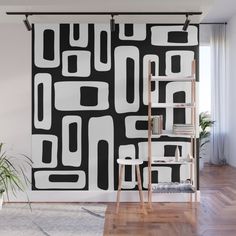 an abstract black and white wall mural in a living room with ladders to the side