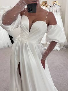 a woman taking a selfie wearing a white dress and holding a cell phone in her hand