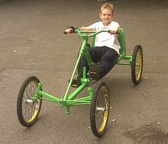 a young boy is riding a green tricycle