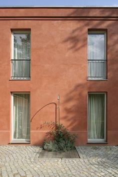 a red building with two windows and a street light in front of it on a brick sidewalk