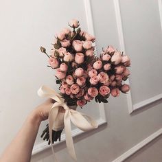 a hand holding a bouquet of pink roses