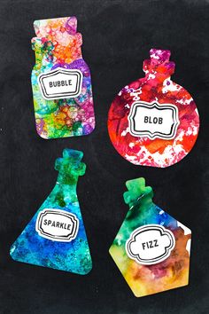 four colorful bottles with labels on them sitting next to each other in front of a black background