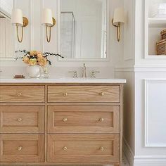 a bathroom vanity with two sinks and large mirror above it, along with gold sconces