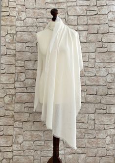 Our ivory bridal shawl is the perfect accessory for your special day. A lightweight beach wedding pashmina shawl that offers elegance and comfort is ideal for summer brides. This raw edge stole features a simple yet sophisticated design, adding a touch of refinement to your ensemble. With this ivory wedding wrap, you can wrap it around your arms or drape it over your shoulders. Your allure will be beautifully enhanced with this bridal pashmina scarf, whether you are walking down the aisle or cel White Pashmina Dupatta Shawl, White Pashmina Shawl With Traditional Drape, White Pashmina Shawl In Traditional Drape, Elegant Cream Pashmina Shawl In Traditional Drape, Elegant White Pashmina Dupatta, Cream Pashmina Dupatta For Wedding, Pashmina Shawl For Wedding In Traditional Drape, Beige Pashmina Shawl Dupatta For Wedding, Wedding Pashmina Shawl In Traditional Style