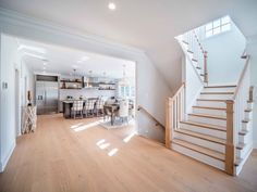 an open floor plan with white walls and wood floors, stairs leading up to the kitchen