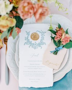 a table setting with place settings, flowers and menu cards on the plates in front of them