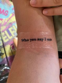 a person with a tattoo on their arm that says, who you say i am?