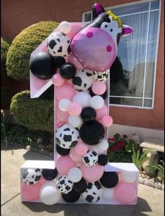 a number one made out of balloons with a cow in the middle and black and white balloons around it