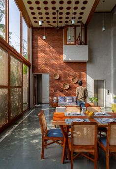 a person sitting at a table in front of a brick wall with lots of windows