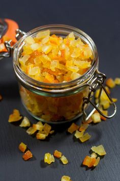 a glass jar filled with chopped carrots sitting on top of a table next to an orange peel