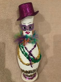 a mardi gras figurine with a purple hat and beads on it