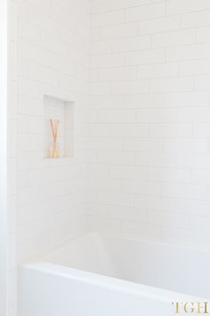 a white bath tub sitting inside of a bathroom next to a wall mounted toilet paper dispenser