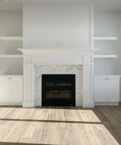 an empty living room with a fireplace and white cabinets