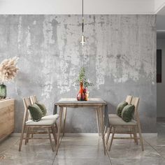 a table with two chairs and vases on it in front of a concrete wall