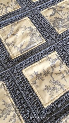 a crocheted blanket with blue and beige designs on it, sitting on top of a wooden table