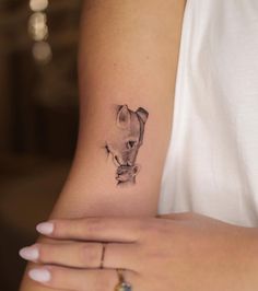 a woman's arm with a small tattoo of a cat on the left side