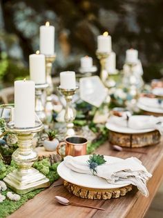 a table with candles, plates and napkins on it