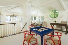 a living room filled with furniture and a blue table in front of a window on top of a stair case