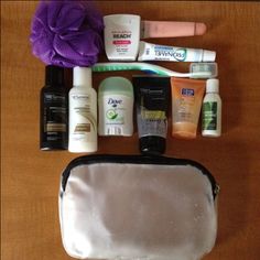 an assortment of personal care products laid out on a wooden table with a purple flower