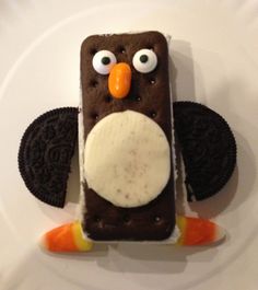 an ice cream sandwich decorated to look like a penguin with googly eyes and carrots