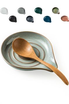 a wooden spoon sitting on top of a green plate next to different colors of saucers