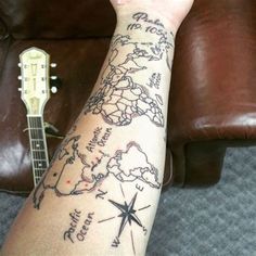 a person's arm with a map on it and a guitar in the background