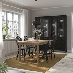 a dining room table with four chairs and a vase on the table in front of it