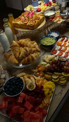 an assortment of fruits and pastries displayed on a table with other foods in bowls