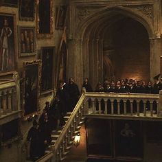 a group of people standing on top of a staircase in an old building with paintings