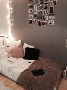 a bed with white sheets and pillows in a room that has pictures on the wall