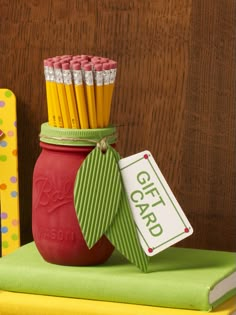 a jar with pencils in it sitting on top of a green table cloth next to a