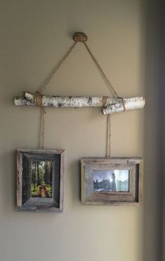 two framed pictures hanging on a wall next to a wooden stick with rope and twine