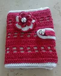 a crocheted red and white case with flower on it sitting on a table