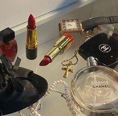 the contents of a chanel purse, lipstick, watch and other items are on display