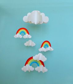 paper clouds and rainbows are hanging from the ceiling in front of a blue wall