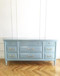 a blue dresser sitting on top of a hard wood floor next to a white wall