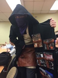 a person in a hoodie is holding up a jacket with several books on it