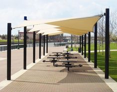 an empty picnic area with tables and umbrellas on the side walk in front of it